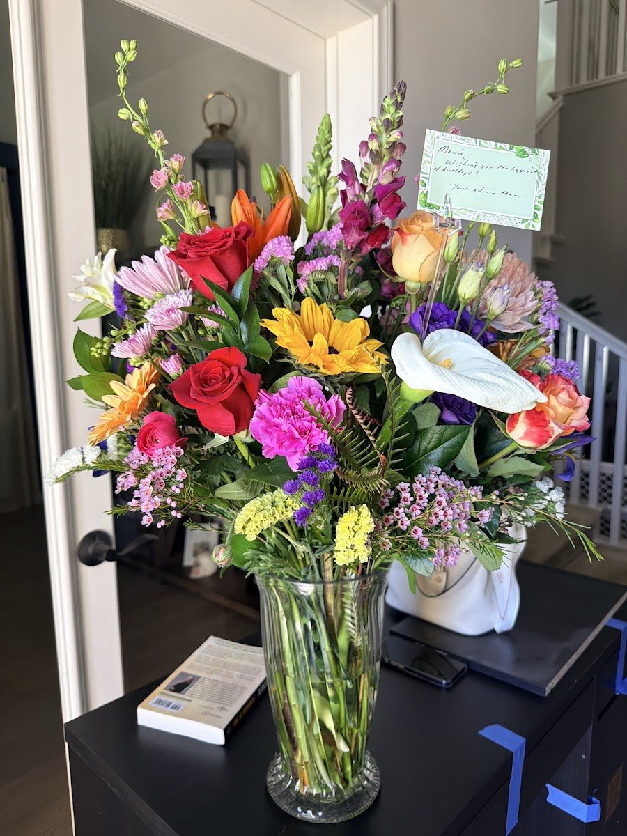 Tall colorful mixed arrangement in a glass vase