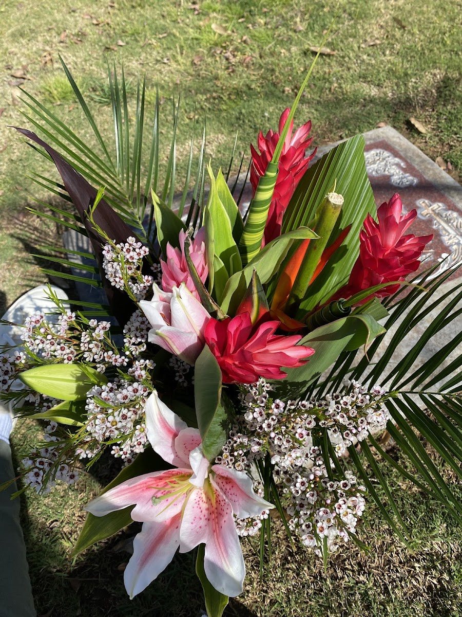 Tropical arrangement with red ginger, pink lilies and palm leaves